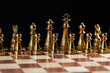 Golden chess figures standing on chessboard