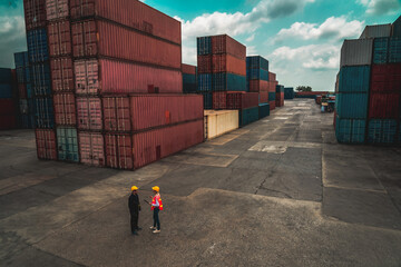 Industrial worker works with co-worker at overseas shipping container yard . Logistics supply chain...