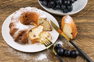 classic cake decorated with powdered sugar on a white plate with cutlery fork and knife.