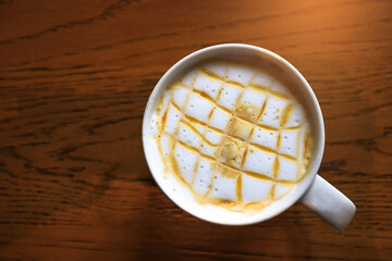 Top view Hot caramel macchiato coffee in the white cup on wooden table background. Drinks concept.