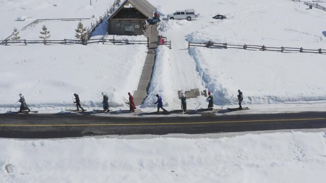 A group of Tuva men dressed in traditional deel walking in fur skis through icy road in Hemu Village, Xinjiang, China on winter day.