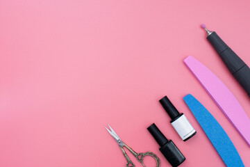 Set of cosmetic tools for manicure and pedicure on a pink background. Gel polishes, nail files, nail scissors, nippers on top. copy space