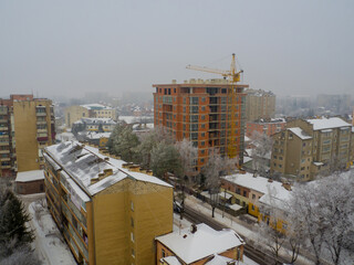 Ivano-Frankivsk City view on a snowy winter day with fog. Tower crane and building construction site at day. New construction site with crane. Building background.