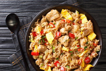 Peruvian fried rice with chicken, omelet, peppers and onions close-up in a bowl on a wooden table. horizontal top view from above