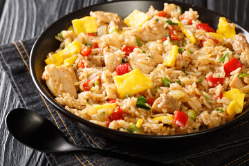 Peruvian fried rice with chicken, omelet, peppers and onions close-up in a bowl on a wooden table. horizontal