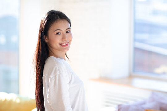 Portrait of smiling asian woman on apartment interior background.