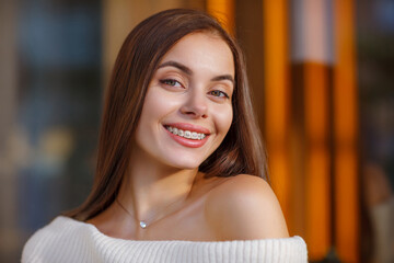 portrait of a beautiful happy smiling young woman with braces. girl bracket system  outdoor. Brace, bracket, dental care, malocclusion, orthodontic health concept. Blurred Details - obrazy, fototapety, plakaty