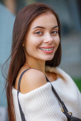 Beautiful Sexy Woman Wearing Fashionable Spring Or Fall Clothes  - White Warm Fluffy Sweater Dress. Outdoors Female Model In Stylish Elegant Outfit Posing In Street Look In Camera.. Blurred Details