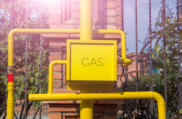 Yellow gas meter box with pipes and valves outdoors. Anti-vandal metal box, gas equipment. Copy space for text