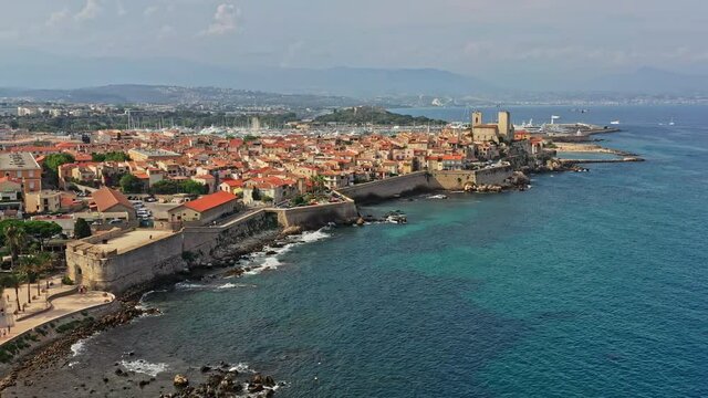Antibes France Aerial v37 establishing shot drone flying along coastal medieval ramparts overlooking at downtown cityscape and picasso museum toward port vauban - July 2021