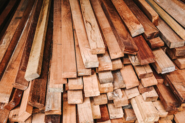 Pile of new wooden bars at construction site. Wood timber construction material texture. Stack of lumbers.