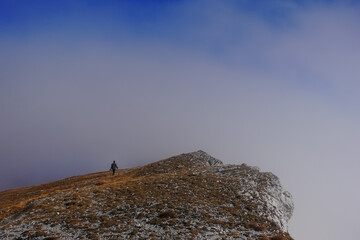 hiker on the top from a mountain with dense fog on the horizon