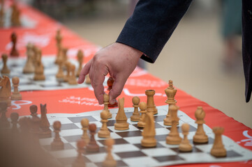 Man holds a chess piece with his hand. Chess board. Chess tournament