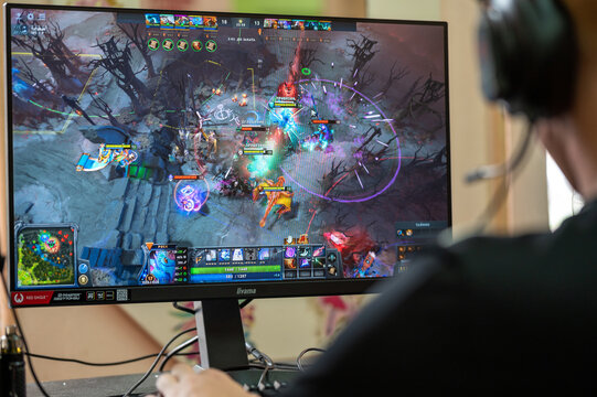Focus on Hands, Keyboards and Mouse. Back view of young gamer playing video game wearing headphone using his controller. Gaming keyboard with RGB light. Gamer's Workspace