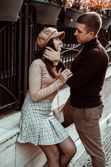 Candid portrait of fashionable couple. Man and woman watching to each other on background of city street. Autumn dating. Love and happiness.