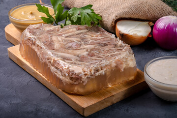 Chicken and turkey jellied meat with garlic, served on a wooden board and horseradish.