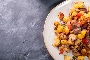 Plate with fried potatoes and mushrooms, meat with a beautiful golden crust, top view, free space.
