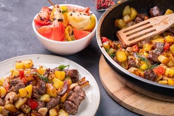 Freshly cooked roast potatoes, mushrooms and meat in a pan and plate.