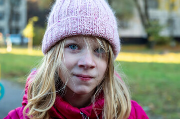 portrait of an eight-year-old girl with disheveled hair on the street on an autumn day