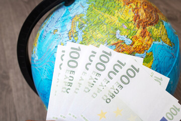 Stack of euro on background of globe with map
