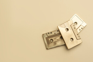Gold fancy retro old audio cassettes tape on beige color background. Retro mixtape, 1980s pop songs...