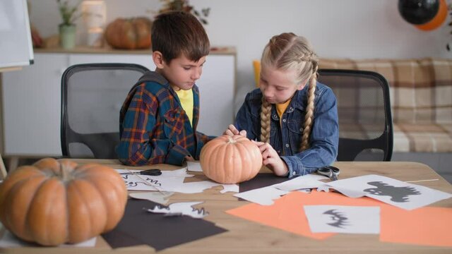halloween, children cut out pictures to decorate the room and draw a pumpkin face with a felt-tip pen to celebrate the autumn holidays