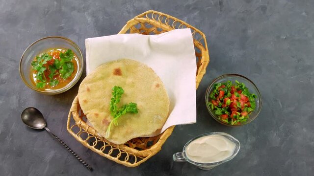 Homemade corn flatbread female hand cilantro greens tomato salsa. Handmade mexican tortillas vegetable salad Traditional Indian Punjabi Makki ki roti bread plate 4K Wheat flour dough authentic cuisine