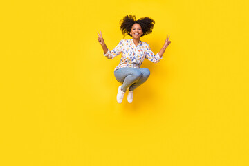 Fototapeta na wymiar Full body photo of cool millennial curly hairdo lady jump show v-sign wear blouse jeans footwear isolated on yellow background