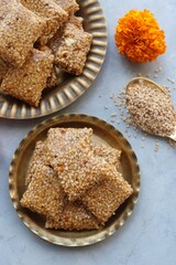 Indian makar sankranti or Lohri festival sweets. Tilgul in a small brass plate. Tilgul is made out of sesame seeds, peanuts, ghee, and jaggery. Til gud chikki or sesame candy. Copy Space. Winter food.