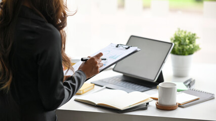 Business woman holding clipboard, looking the informations on paperwork