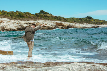 man walking by rocky beach in windy day summer vacation. enjoy sea view