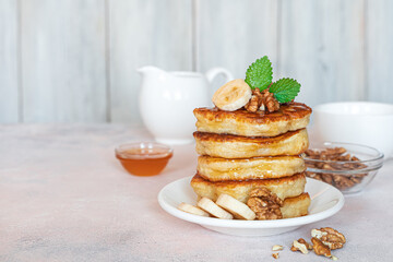 Breakfast with pancakes with honey and nuts on a light background.
