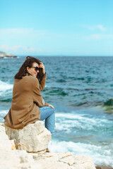 Fototapeta na wymiar woman sitting on cliff enjoying view of the sea. windy weather. sunny day