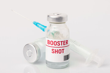 Bottle with covid-19 booster dose of vaccine, a syringe on the table. Concept of 3rd booster dose of vaccine