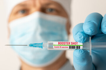 Doctor holding syringe with Covid-19 vaccine with inscription booster shot. Concept of third booster dose of vaccine - obrazy, fototapety, plakaty