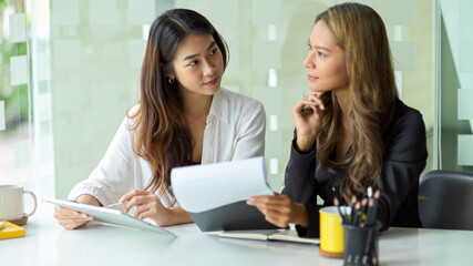Two attractive businesswomen are meeting in the office.