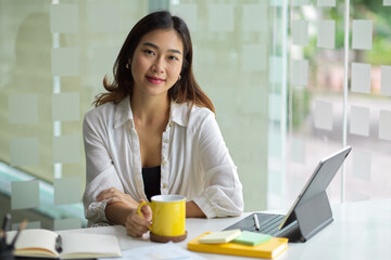 Female entrepreneur sits at her office work station with portable tablet
