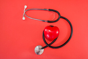 Stethoscope, red heart and place for text on a red background, flat lay.