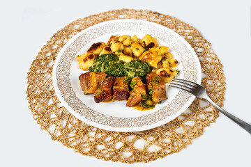 Baked pork meat, stewed spinach and roasted gnocchi (dumplings) on plate.