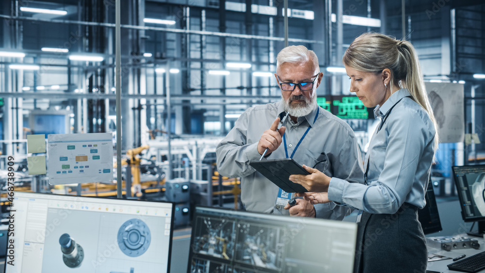 Fototapete Car Factory Office: Scientist Talks with Senior Engineer, Use Tablet Computer to Design Production Conveyor for Advanced Power Engines. Automated Robot Arm Assembly Line Manufacturing Vehicles