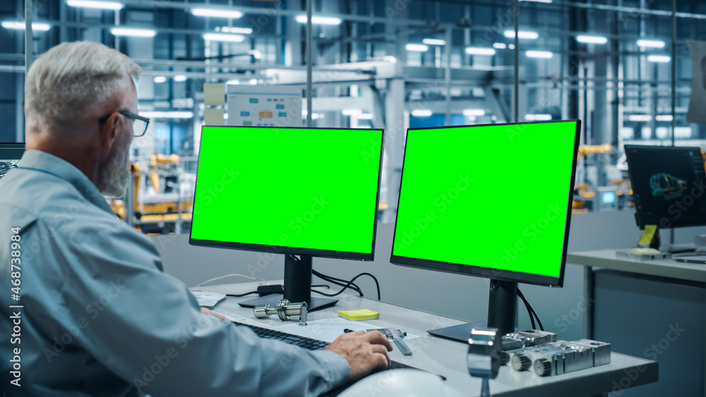 Poster car factory monitoring office: male chief automotive engineer sitting at the desk working on green s