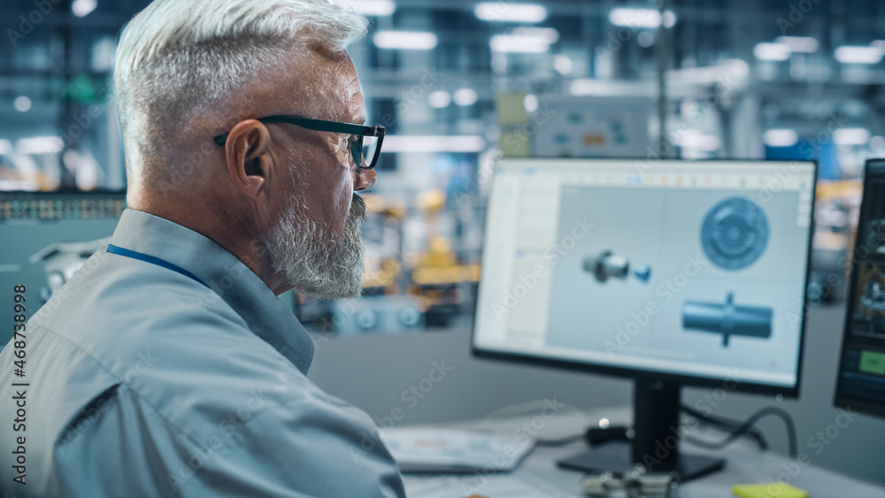 Poster car factory office: male chief automotive engineer sitting at his desk working on computer. monitori