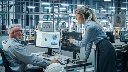 Car Factory Office: Female Project Manager Talks to Male Chief Automotive Engineer Working on Computer. Monitoring, Control, Equipment Design. Automated Robot Arm Assembly Line Manufacturing Vehicles