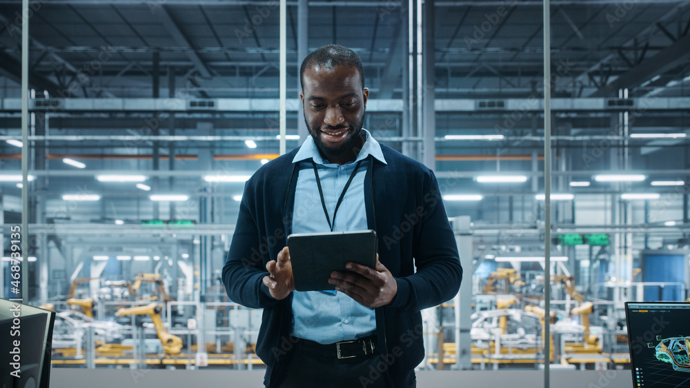 Poster car factory office: portrait of successful black male chief engineer using tablet computer in automa