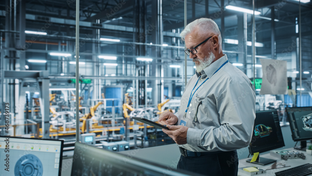 Poster car factory office: portrait of senior white male chief engineer using tablet computer in automated 