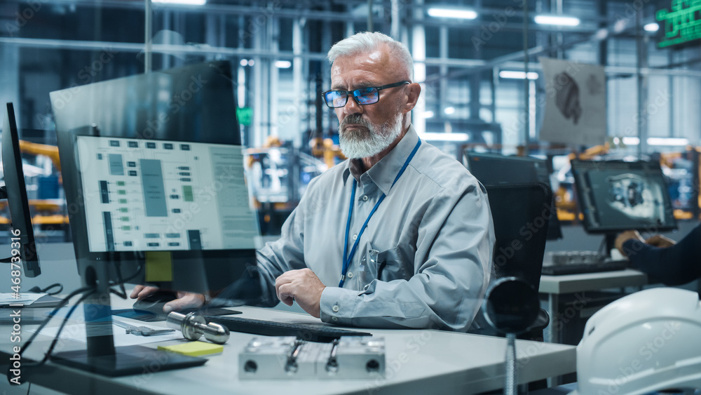 Poster car factory office: portrait of senior male chief engineer working on desktop computer in automated 