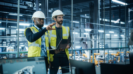 Car Factory: Project Manager and Automotive Engineer in Hard Hat, Talking, Using Laptop....