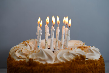 Burning candles on top of a honey cake. Beautiful white candles lit for the birthday - 468739533