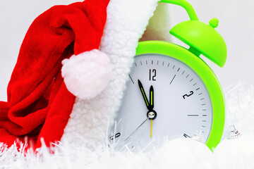 Alarm clock with Santa hat and Christmas decorations isolated on gray white background.New Year 2022 concept.Close up.