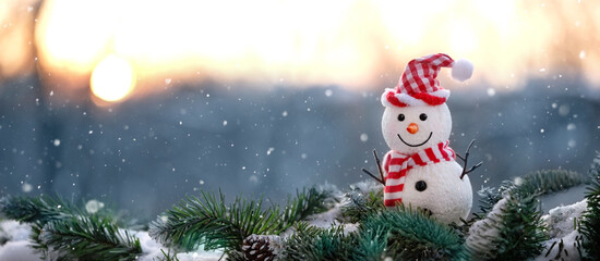 cute snowman toy on snowy fir tree, winter natural background. Christmas and New year holiday....